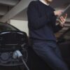 man using digital tablet while charging electric car